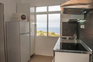 a kitchen with a refrigerator and a sink and a window at Villa SCIROCCO Madeira - Ocean View in Machico