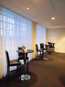 - une salle d'attente avec des tables, des chaises et des rideaux dans l'établissement Fletcher Hotel-Restaurant Parkstad- Zuid Limburg, à Kerkrade