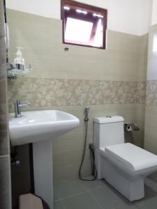 a bathroom with a toilet and a sink and a window at Otha Shy Airport Transit Hotel in Katunayake