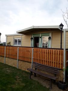 une maison avec une clôture en bois et un banc dans l'établissement Chalet am IJsselstrand, à Doesburg