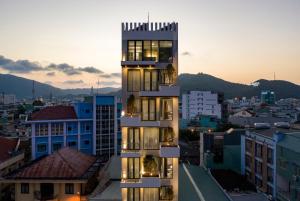 un edificio alto en una ciudad al atardecer en HAKU Boutique Hotel Quy Nhơn - Lê Lợi, en Quy Nhon