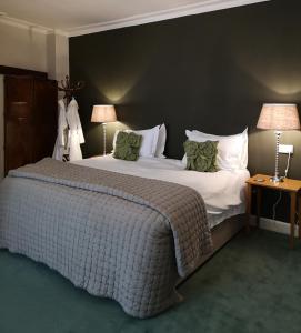 a large bed in a hotel room with two lamps at The Priory in Middleham