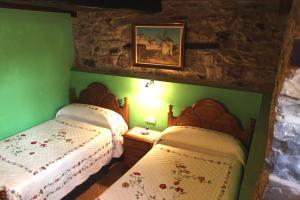 two beds in a bedroom with green walls at Casa Rural La Torre de Espinama in Espinama +25 photos