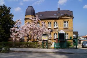 ein Gebäude mit einem blühenden Baum davor in der Unterkunft Hotel Am Kurpark in Bad Suderode