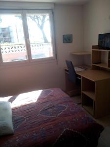 1 dormitorio con cama, escritorio y ventana en Appartement en bord de mer en Port-la-Nouvelle