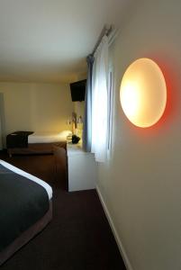 ein Schlafzimmer mit einem Bett und einer Lampe an der Wand in der Unterkunft Campanile Paris Ouest - Chaville in Chaville