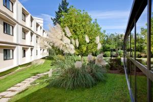 een tuin met gras en planten naast een gebouw bij ibis Styles Chalon sur Saône in Chalon-sur-Saône