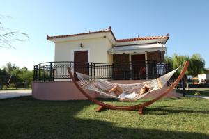 a woman laying in a hammock in front of a house at Kalloni village apartments in Skala Kallonis