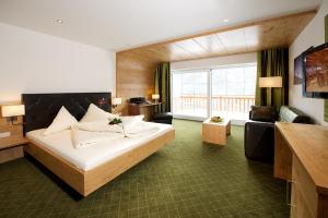 a hotel room with a bed and a large window at Berg-Spa & Hotel Zamangspitze in Sankt Gallenkirch