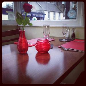 twee rode vazen op een houten tafel bij Aberdour Hotel, Stables Rooms & Beer Garden in Aberdour