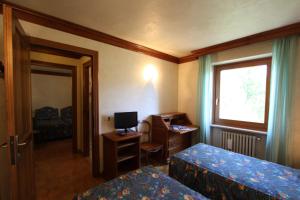 1 dormitorio con 2 camas, escritorio y ventana en Hotel Panoramique en Torgnon