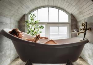 Eine Frau, die in einer Badewanne im Fenster liegt. in der Unterkunft Apartment Masoch Style in Lwiw