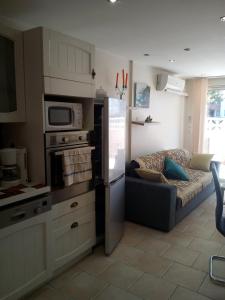 a kitchen with a refrigerator and a couch in it at Appartement en bord de mer in Port-la-Nouvelle