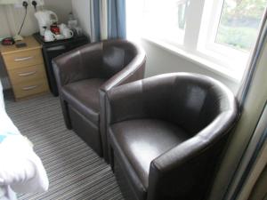 two leather chairs sitting next to a window at Gate Lodge Guest House in Hunstanton