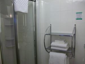 a bathroom with a shower and some towels on a shelf at Gate Lodge Guest House in Hunstanton