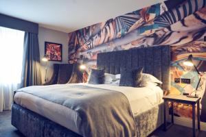 a bedroom with a large bed with a colorful wall at Malmaison Belfast in Belfast