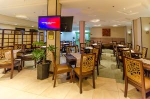 a restaurant with wooden tables and chairs and a tv at Microtel by Wyndham General Santos in General Santos