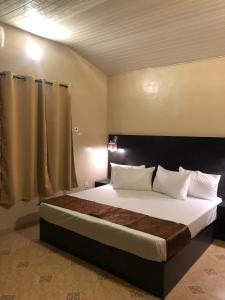 um quarto com uma cama grande e almofadas brancas em Posh Apartments Business Hotel em Ikeja