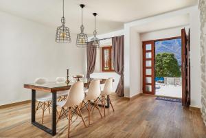 a dining room with a table and white chairs at Three Dots by Todorovic Family in Kotor