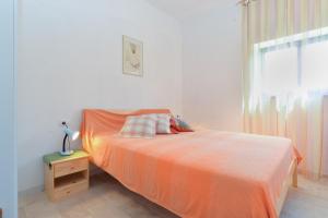 a bedroom with a bed with an orange blanket and a window at House Rakalj 1829 in Rakalj +21 photos