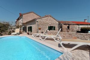 a swimming pool with chairs and a house at House Rakalj 1829 in Rakalj