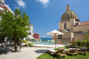 a pool with chairs and an umbrella next to a building at Hotel Palazzo Murat in Positano