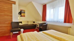 a hotel room with a bed and a couch at Hotel KRONE Garni in Deckenpfronn