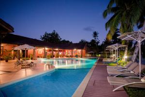 a swimming pool with chairs and umbrellas at night at Mantis Soanambo Hotel And Spa in Ambondrona