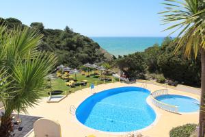 a swimming pool with the ocean in the background at Rocha Brava Village Resort in Carvoeiro