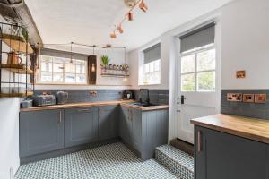 eine Küche mit blauen Schränken und einer Spüle in der Unterkunft 3 MASONS COURT The Oldest House in Stratford Upon Avon, Warwickshire. in Stratford-upon-Avon + 11 Fotos