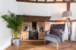 ein Wohnzimmer mit einem Stuhl und einem Kamin in der Unterkunft 3 MASONS COURT The Oldest House in Stratford Upon Avon, Warwickshire. in Stratford-upon-Avon