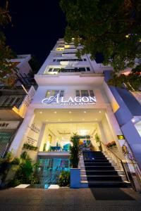 a large white building with a neon sign on it at Alagon Saigon Hotel & Spa in Ho Chi Minh City