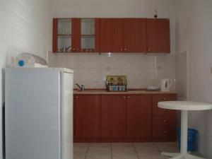 eine Küche mit Holzschränken und einem weißen Kühlschrank in der Unterkunft Apartments Lončarević in Slano