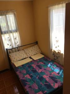 a small bed in a room with two windows at Pines Mansion 2 Homestay for Rent in Cash with 30 percent Advance Payment to Confirm in Butuan