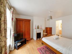 パリにあるWelkeys - Choiseul Apartmentのベッドルーム(ベッド1台、テレビ、暖炉付)