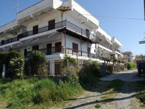 a white building with a balcony on a street at Aparts Sunshine in Nea Iraklia