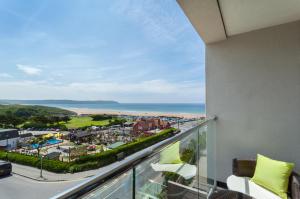 a balcony with a view of a city and the ocean at 8 Woolacombe West - Luxury Apartment at Byron Woolacombe, only 4 minute walk to Woolacombe Beach! in Woolacombe