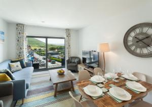 a living room with a table and a clock on the wall at 8 Woolacombe West - Luxury Apartment at Byron Woolacombe, only 4 minute walk to Woolacombe Beach! in Woolacombe