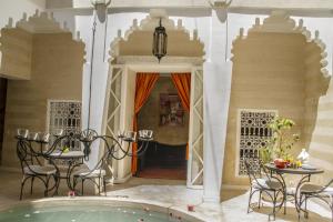 a room with a tub and a table and chairs at Riad THALGE in Marrakesh
