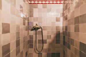 y baño con ducha y azulejos marrones y blancos. en El Riad Andaluz, en Málaga