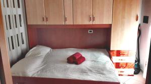 a red bow on a white bed with wooden cabinets at Appartamento Maestri in Sottomarina +29 photos