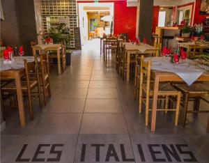 Un comedor con mesas y sillas de madera. en Hôtel Les Italiens, en Biscarrosse