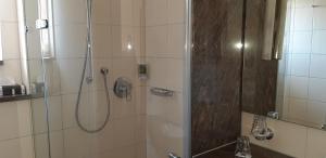 a bathroom with a shower with a glass door at Hotel Rauch in Ettringen +8 photos