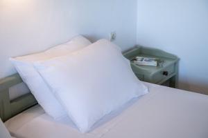 a white pillow sitting on a bed with a night stand at Androulakis Apartments in Gerani