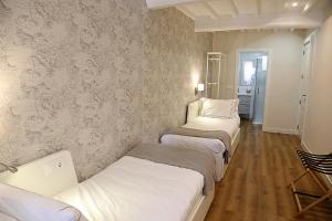 a room with three beds and a wall with wallpaper at Casa Herreria in Caldas de Reis
