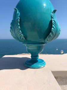 un vaso di vetro blu, seduto sopra un cornicione. di Trame - Poesia Di Mare a Polignano a Mare