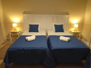 two beds with blue and white pillows in a room at Lagoa´s House in Lagoa