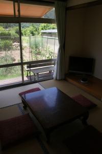 uma sala de estar com uma mesa e uma grande janela em Shinshu Wakaho Gibier B&B em Nagano