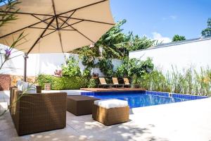 a patio with an umbrella and chairs and a pool at Pousada Villa Magnolia in São João del Rei