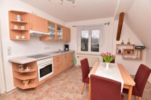 una cocina con armarios de madera y una mesa con sillas. en Ferienwohnung am Hafen, en Lübbenau